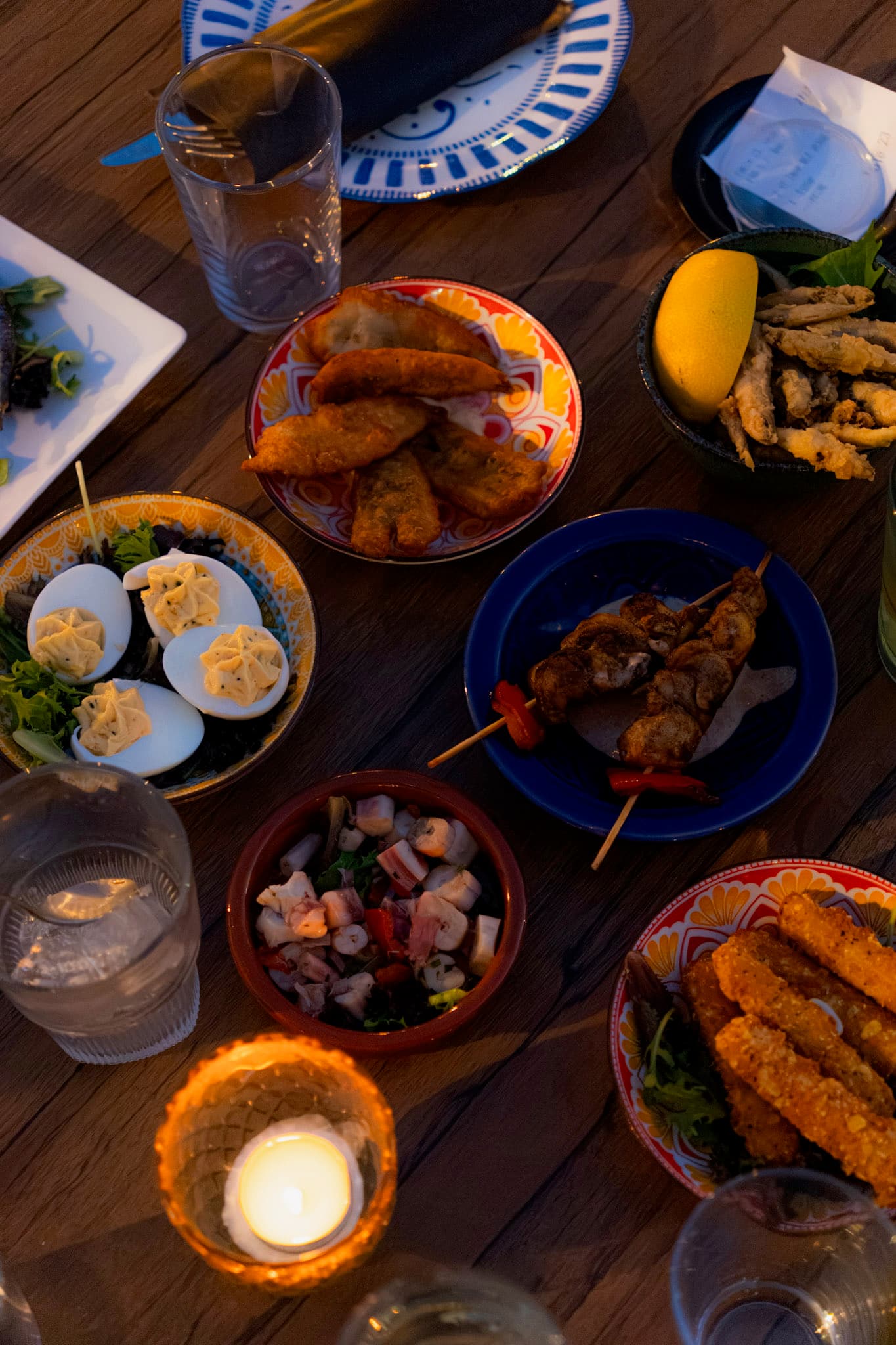La table garnie de petites assiettes, à la bougie